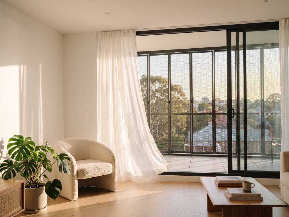 Living room with a security screen closed across the balcony opening, breeze coming through